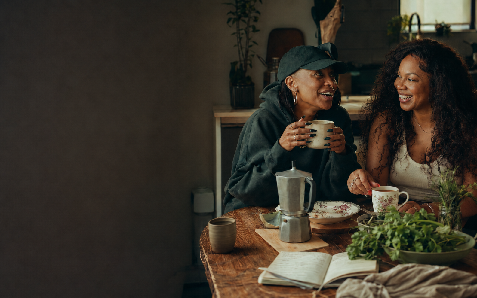 Two Black women sharing coffee, conversation, and recipes around a Sunday table